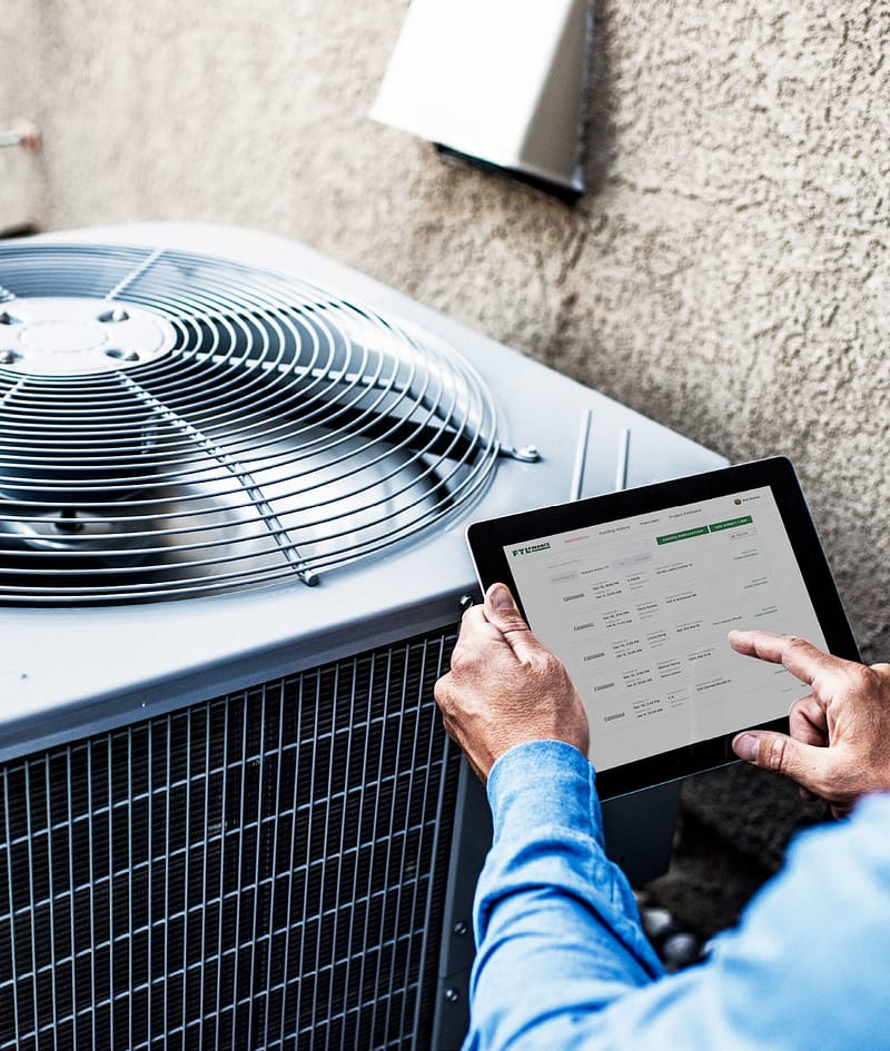 Man standing infront of an A/C unit holding a tablet
